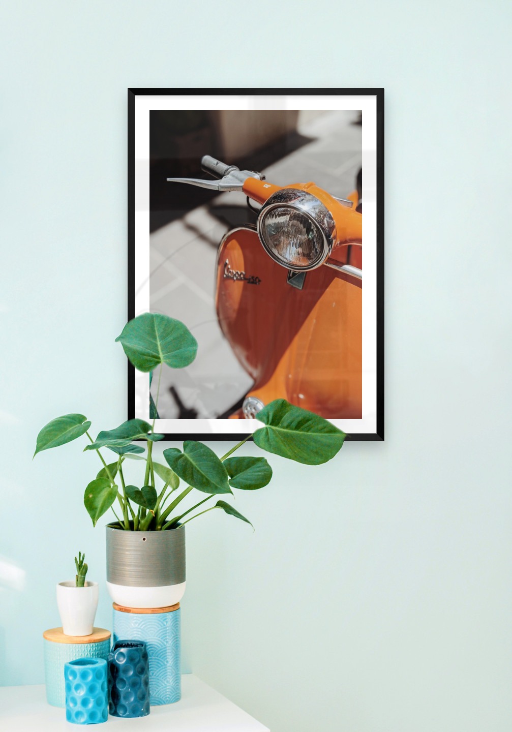 Tavelvägg med ram i svart i storlek 50x70 med poster med "Orange vespa"