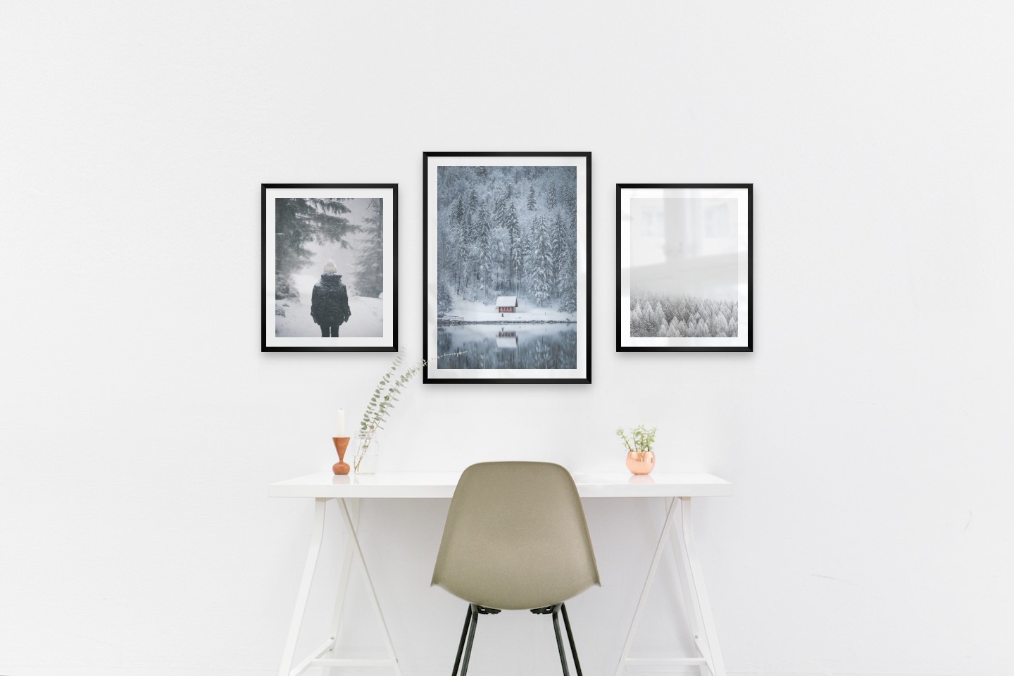 Tavelvägg med ramar i svart i storlekar 40x50 och 50x70 med posters med "Person i snön", "Stuga vid sjö" och "Trätoppar i vintern"