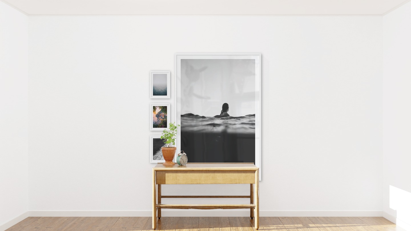 Tavelvägg med ramar i vitt i storlekar 21x30 och 100x150 med posters med "Dimma över havet", "Stad vid havet", "Svall från vågor" och "Person i vattnet"